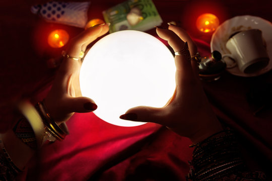 Hands of fortune teller with crystal ball in the middle