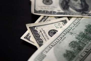 A pack of hundred dollar bills on a dark background