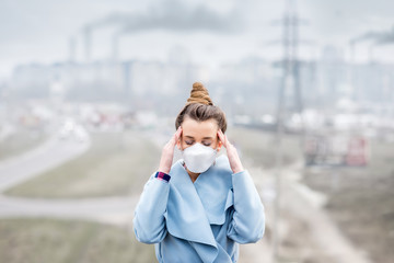 Young woman in protective mask feeling bad in the city with air pollution from traffic and...