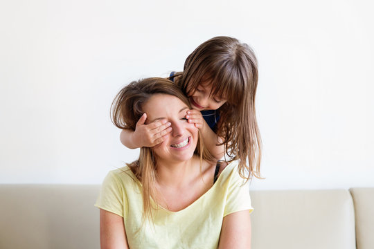 smiling little girl hiding her mother's eyes