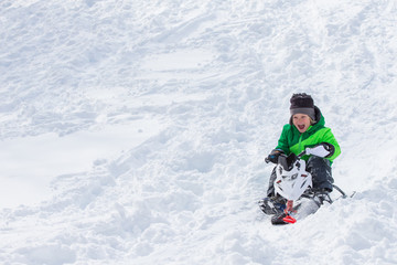 Fototapeta na wymiar Boy riding a sled tobogganing in the snow