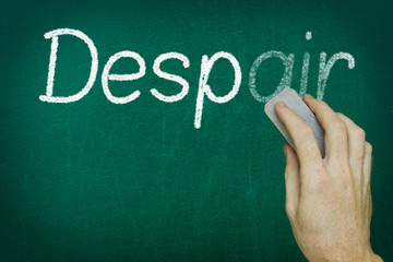 Hand erasing the word DESPAIR written on blackboard