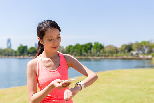 Woman connecting cellphone and smart watch - Powered by Adobe