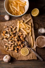 Deurstickers Mussels with lemons and French fries on the metal background vertical © deniskarpenkov