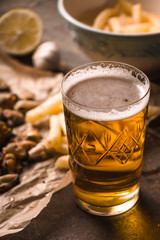 Glass of beer with blurred snack on the metal background