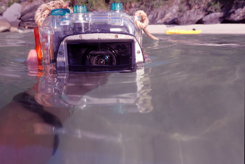 Compact camera and housing floating on the sea with reflections surface. 
