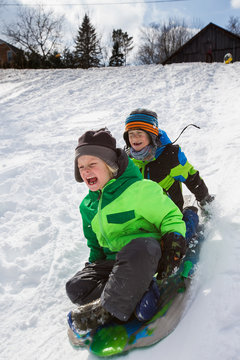 Boys riding a sled, tobogganing down the snow