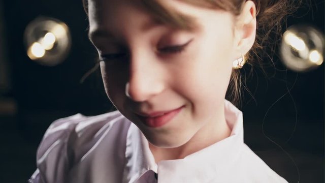Cute girl face close to the camera changing emotions. Black background.