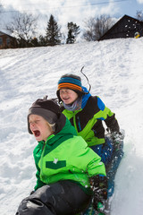 Boys riding a sled, tobogganing down the snow