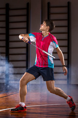 Badminton player beats the shuttlecock in the gym