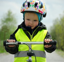 Happy boy learns to ride a bike on a bike trail in the nature. He has a helmet because of safety....
