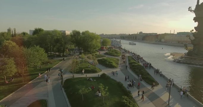 Aerial view of Peter the Great Statue on a spring day at sunset. Crowds of people walking along the park near river.