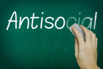 Hand erasing the word ANTISOCIAL written on blackboard