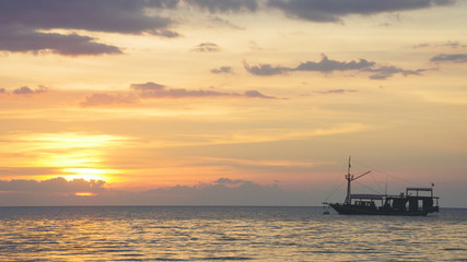Fototapeta na wymiar Boat silhouette crossing the ocean towards an orange sunset sky on the horizon, Labuan Bajo Bajawa.