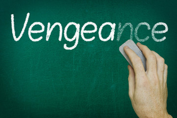 Hand erasing the word VENGEANCE written on blackboard