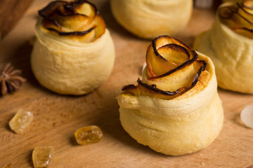 Fresh cinnamon buns with apples on the rustic wooden background. Shallow depth of field.