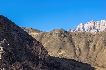 Fototapeta na wymiar Горный пейзаж, красивый вид на высокие скалы освещенные солнцем, горы и природа Северного Кавказа