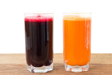 Two glass of fresh beet and carrot juice on wooden table, white background.