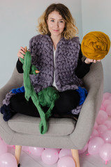 young woman sitting on chair and holding merino wool in hands