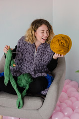 young woman sitting on chair and holding merino wool in hands