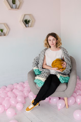 young woman sitting on chair and holding merino wool in hands