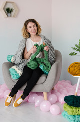 young woman sitting on chair and holding merino wool in hands