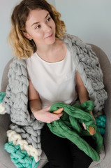 young woman sitting on chair and holding merino wool in hands