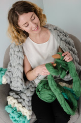 Young woman sitting and kniting with merino wool