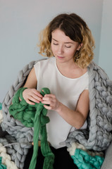 Young woman sitting and kniting with merino wool