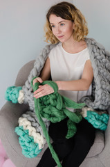 Young woman sitting and kniting with merino wool