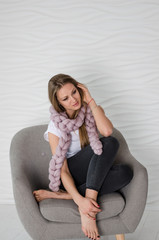 Beautiful woman in soft pink merino wool scarf sitting on arm chair