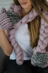 Beautiful woman in soft pink merino wool scarf, hat and gloves sitting on arm chair