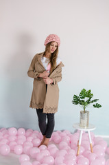 beautiful woman in pink merino wool hat with balloons on floor