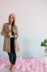 beautiful woman in pink merino wool hat with balloons on floor