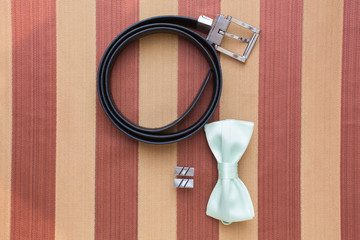 accessories of men's wear. Brown leather belt, bow-tie of green color and cuff link. Morning of the...