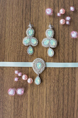 woman's accessories. Earrings with green stones, a necklace and pink pearls.
