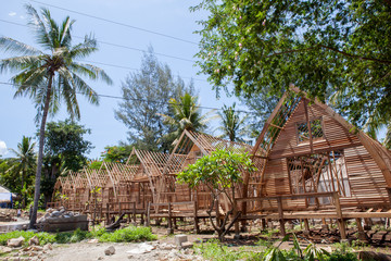 Obraz premium The construction of the guest houses is made from natural resources on the beach with palm trees.