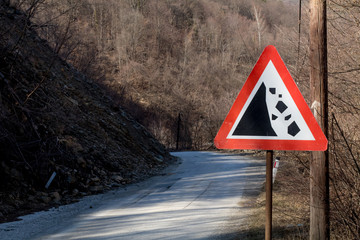 Landslide road sign in the mountains on the hill, clay, village, forest. Danger falling stones.