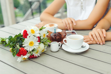 Chocolate muffin with one candle, cups with coffee on wooden table .