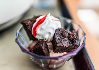 Small brownie bowl with whipped cream and cherry sauce topping