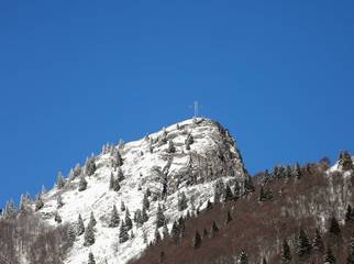Fototapeta premium snow covered peak of the highest mountain with a cross on top