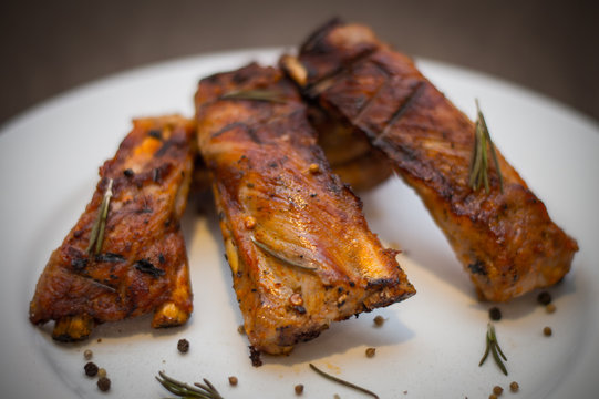 Pork ribs, BBQ grilled, with seasonings on a white ceramic plate