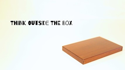 Think Outside the Box Words with Wood Container Laying Flat on Plain Backdrop