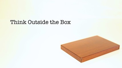 Think Outside the Box Words with Wood Container Laying Flat on Plain Backdrop