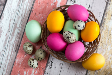 Still life: Easter and quail eggs in a basket: yellow, pink, green. Spring.