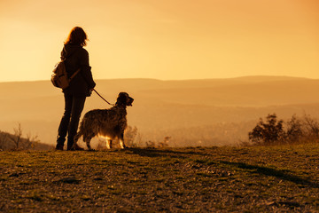 Woman with her english setter dog on a mountain looking at the autumn landscape
