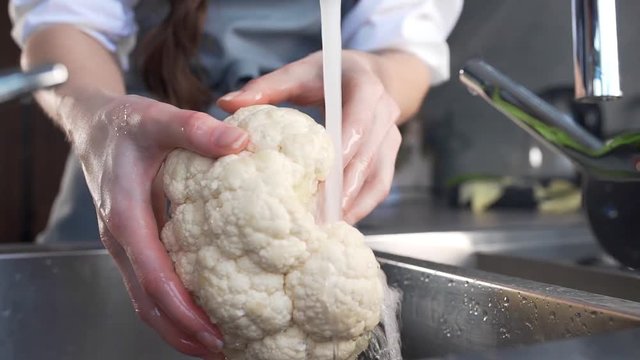Chef washes cauliflower for vegetable ragout cooking, housewife cooks vegetables, woman makes vegetable salad, fresh and healthy food from kitchen-garden