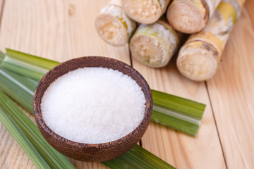 Fototapeta na wymiar White sugar and sugar cane on wooden table background