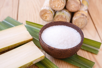 White sugar and sugar cane on wooden table background