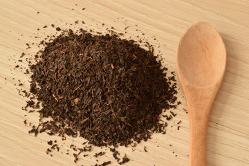 dry black tea leaves and wooden spoon